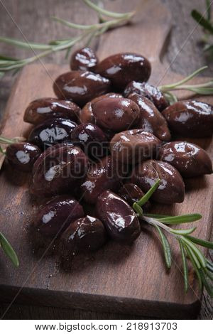 Cured, pickled or brined olive fruit on wooden table