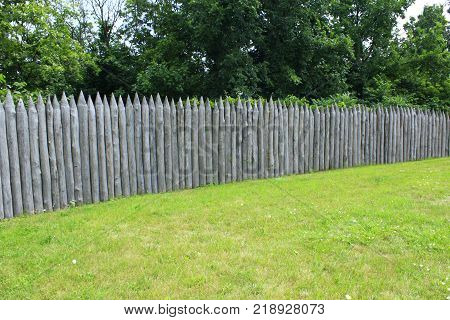 historical protecting fence from wooden logs on the green grass