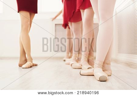Ballet background, young ballerinas training. Female dancers legs in pointe shoes, making exercises. Classical dance school, copy space, crop