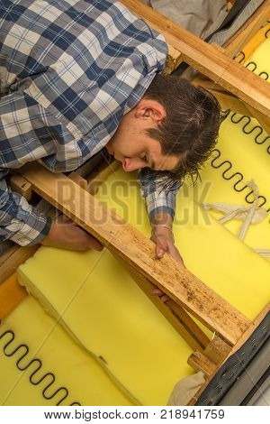 upholsterer padding a sofa with open framing in the upholsterer shop