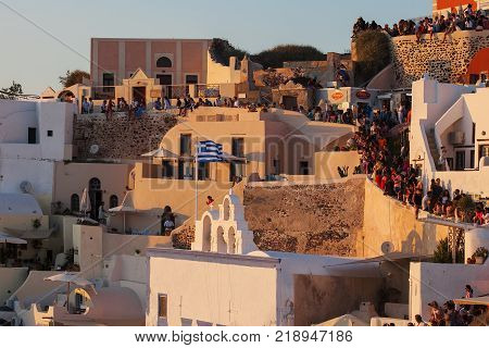 Oia, Santorini, Greece - August 24, 2017: Crowd of tourists awaits the famous sunset in mediteran sea. A view of beautiful sunset from Oia in Santorini, Cyclades islands, Greece, EU