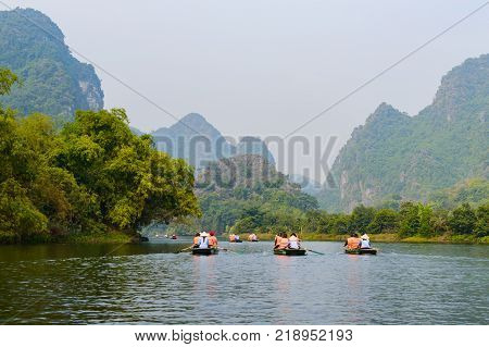 International tourists traveling on local vietnamese small boat along the Ngo Dong river of the Tam Coc, Ninh Binh, Vietnam.