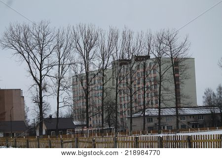 cubical high building hide under line of tree in cloudy winter day