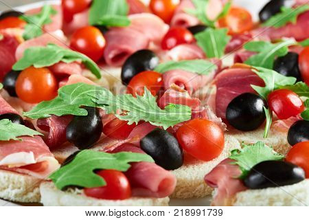 Delicious restaurant appetizer : canapees with white bread, bacon rolls, fresh cherry tomatoes and green parsley leaves. Tasty snack for catering or buffet.