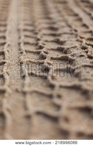 A vehicle tyre track left in the sand with selective focus
