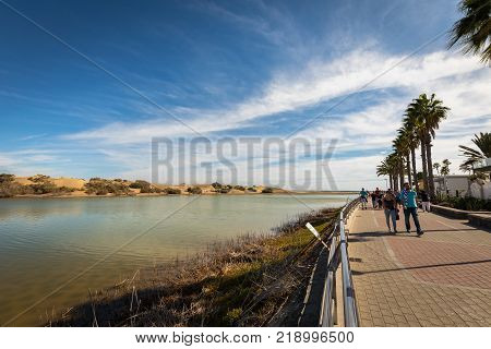 Maspalomas in Gran Canaria, Spain - December 11, 20017: La Charca, bird observation place in Maspalomas Dunes nature reserve. Promenade walk with tourists on the right side.. Great place for bird observations.