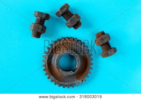 Rusty Bolts, Nuts And Gear Wheel Made Of Chocolate Isolated On Sky Blue Background. Mechanic Gearing