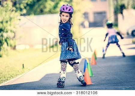 Children Learning To Roller Skate On The Road With Cones.