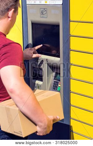 Man Client Using Automated Self-service Post Terminal Machine Or Locker To Depisit A Parcel For Stor