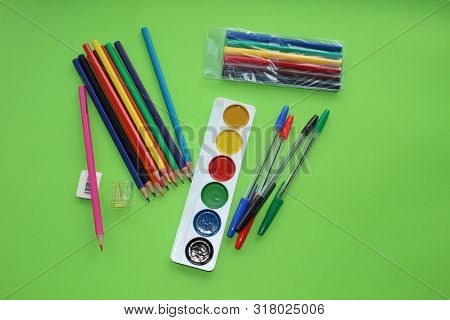 Colored Pens,pencils, Paints, Pens For Writing. Colorful Items For School, Office On A Green Backgro