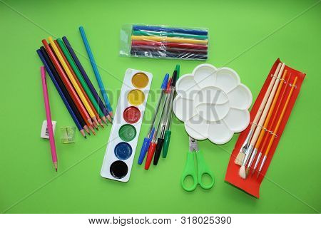 Colored Pens,pencils, Paints, Pens For Writing. Colorful Items For School, Office On A Green Backgro