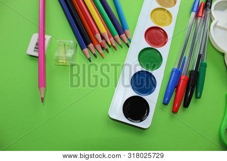 Colored Pens,pencils, Paints, Pens For Writing. Colorful Items For School, Office On A Green Backgro