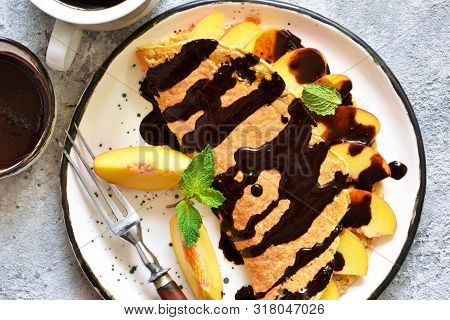 Classic Breakfast - Crepes With Caramel Peaches And Chocolate Sauce. Breakfast And A Cup Of Coffee.