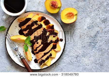 Classic Breakfast - Crepes With Caramel Peaches And Chocolate Sauce. Breakfast And A Cup Of Coffee.