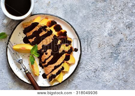 Classic Breakfast - Crepes With Caramel Peaches And Chocolate Sauce. Breakfast And A Cup Of Coffee.