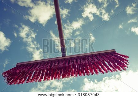 Broom Red Sweeping Brush Against Blue And White Cloudy Sky. Household Obejcts Concept.