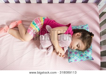 Directly Above Shot Of Small Girl Is Asleep With Teddybear On Bed In Bedroom At Home