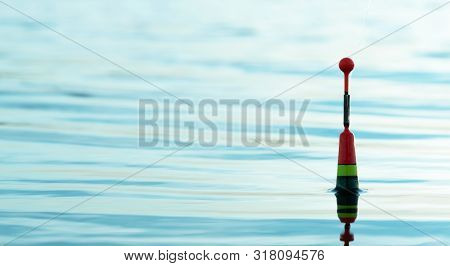 Fishing Float In A Blue Water Close Up Background.