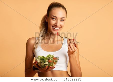Healthy Diet. Smiling Woman Eating Salad Over Pink Studio Background. Free Space For Text