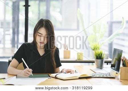 Young Asian graphic designer working on computor and graphics tablet in her working space