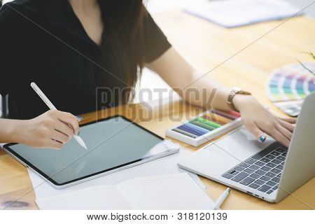 Young Asian graphic designer working on computor and graphics tablet in her working space