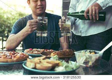 Asian Friends Are Pouring Beer Into The Glass While Friends Are Waiting To Celebrate In Their Home.