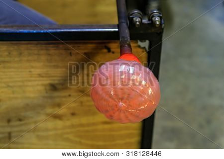 Glass Blower Shaping A Bubble Of Melted Glass On A Rod By Hand In The Manufacturing Process At A Gla