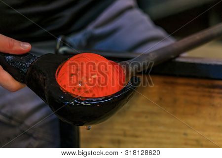 Glass Blower Shaping A Bubble Of Melted Glass On A Rod By Hand In The Manufacturing Process At A Gla