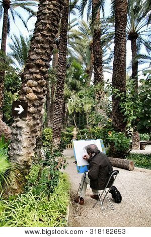 Elche, Alicante, Spain- February 14, 2019: Old Senior Painting And Relaxing In Huerto Del Cura Botan