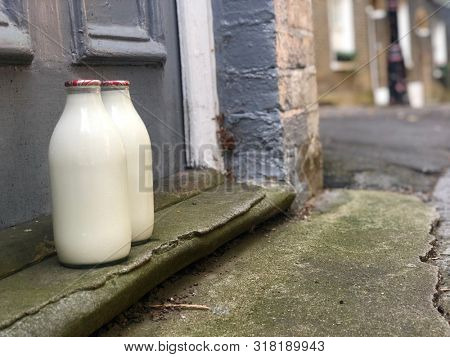 Fresh milk delivered by a milkman on a door step in glass bottles