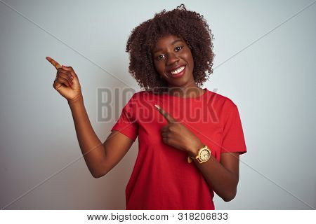 Young african afro woman wearing red t-shirt over isolated white background smiling and looking at the camera pointing with two hands and fingers to the side.