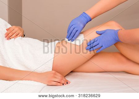 Beautician Waxing Female Legs In Spa Center. Removing Unnecessary Hair On The Legs. Procedure Sugari