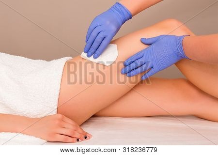 Beautician Waxing Female Legs In Spa Center. Removing Unnecessary Hair On The Legs. Procedure Sugari
