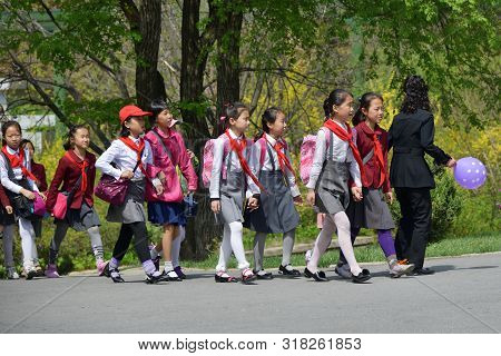 Pyongyang, North Korea - May 1, 2019: Squad Of Pioneer Girls Walking In The Taesongsan Funfair. Is A