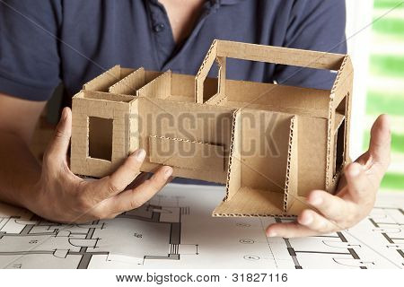 En mandlig arkitekt ser på en model hus