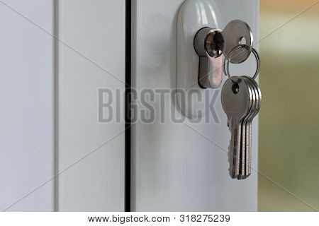 The Key In The Mortise Lock Of A White Plastic Door. The Concept Of Forgetfulness And Distraction Of