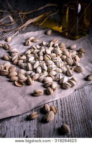 Pistachios On Wooden Table In The Foreground With Darkened Background