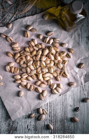 Pistachios On Wooden Table In The Foreground With Darkened Background