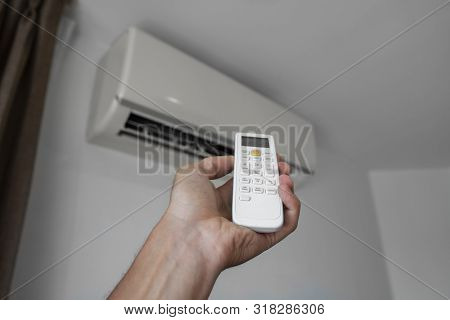 Mans Hand Using Remote Controler. Hand Holding Rc And Adjusting Temperature Of Air Conditioner Mount