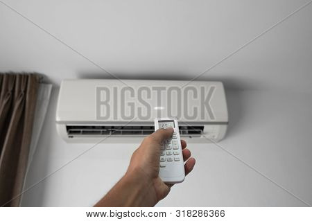 Mans Hand Using Remote Controler. Hand Holding Rc And Adjusting Temperature Of Air Conditioner Mount