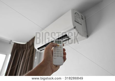 Mans Hand Using Remote Controler. Hand Holding Rc And Adjusting Temperature Of Air Conditioner Mount