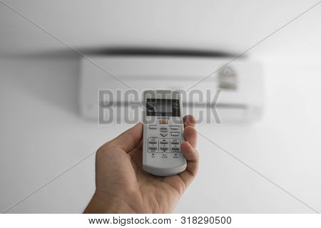 Mans Hand Using Remote Controler. Hand Holding Rc And Adjusting Temperature Of Air Conditioner Mount