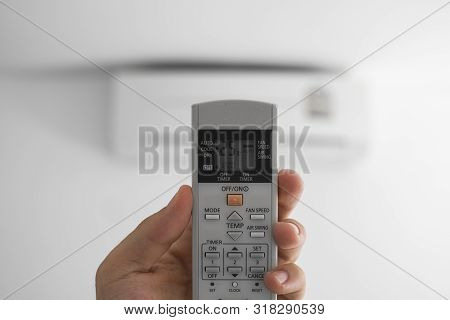 Mans Hand Using Remote Controler. Hand Holding Rc And Adjusting Temperature Of Air Conditioner Mount