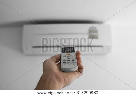 Mans Hand Using Remote Controler. Hand Holding Rc And Adjusting Temperature Of Air Conditioner Mount