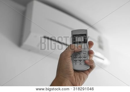 Mans Hand Using Remote Controler. Hand Holding Rc And Adjusting Temperature Of Air Conditioner Mount