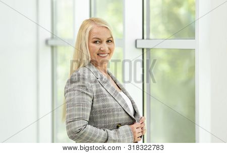 Portrait Of Happy Mature Woman Near Window Indoors