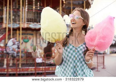 Young Woman With Cotton Candies In Amusement Park. Space For Text