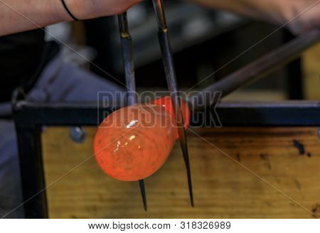 Glass Blower Shaping A Bubble Of Melted Glass On A Rod By Hand In The Manufacturing Process At A Gla