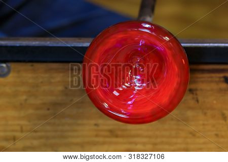 Glass Blower Shaping A Bubble Of Melted Glass On A Rod By Hand In The Manufacturing Process At A Gla