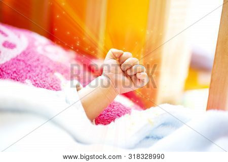 Hand Of An Energetic Newborn Baby With Light Blue And Pink Blanket And Baby Bed. Close Up.